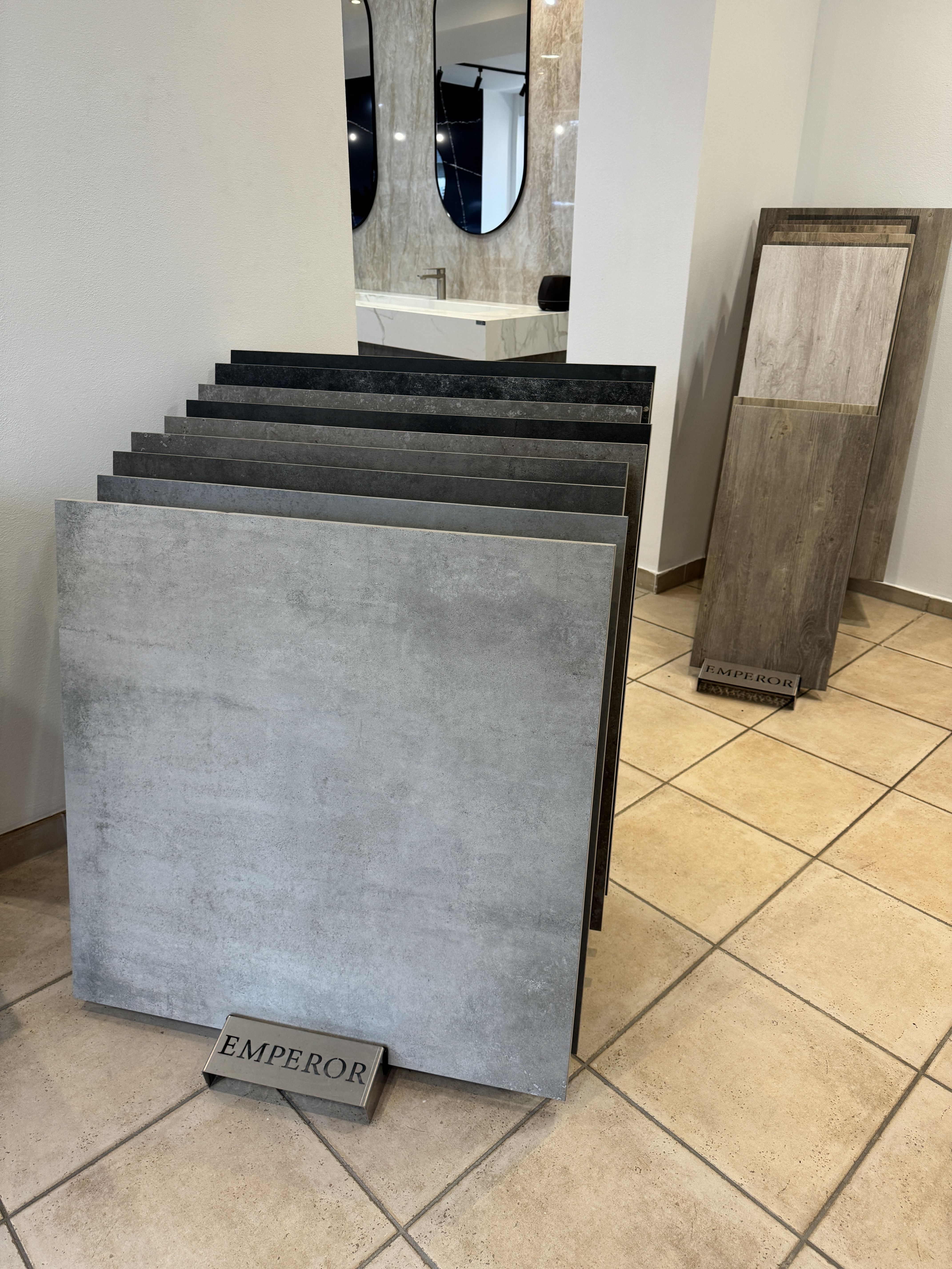 Ausstellung mit stehenden Bodenfliesen, im Vordergrund eine graue Fliese mit Schild „EMPEROR“.